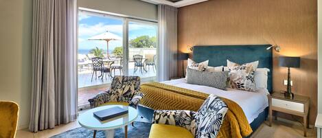 A hotel room with a large bed, a sofa, a small table, and a view of the outdoors.