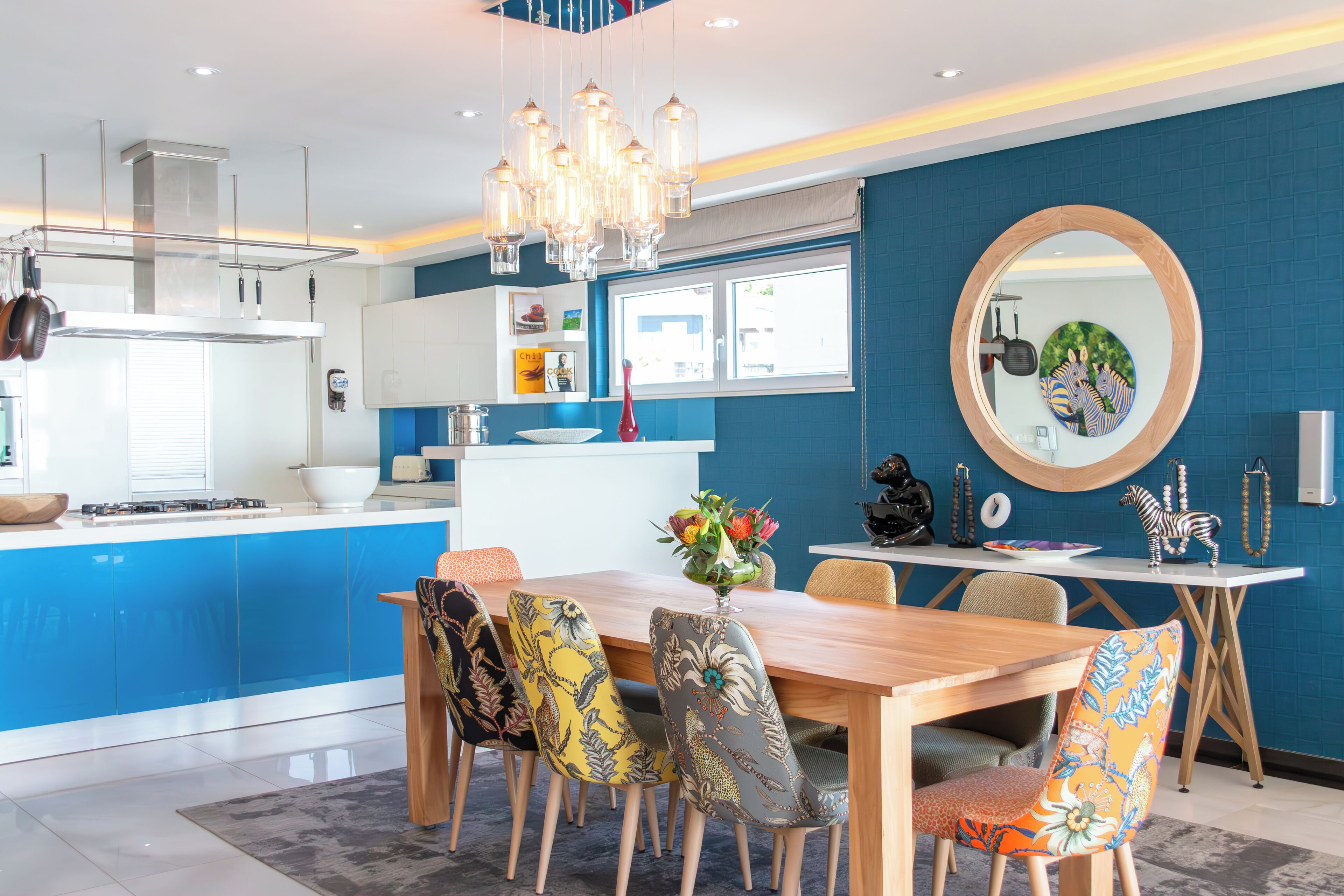 Eine moderne Küche mit blauen Schränken, einem Holztisch und bunten Stühlen.