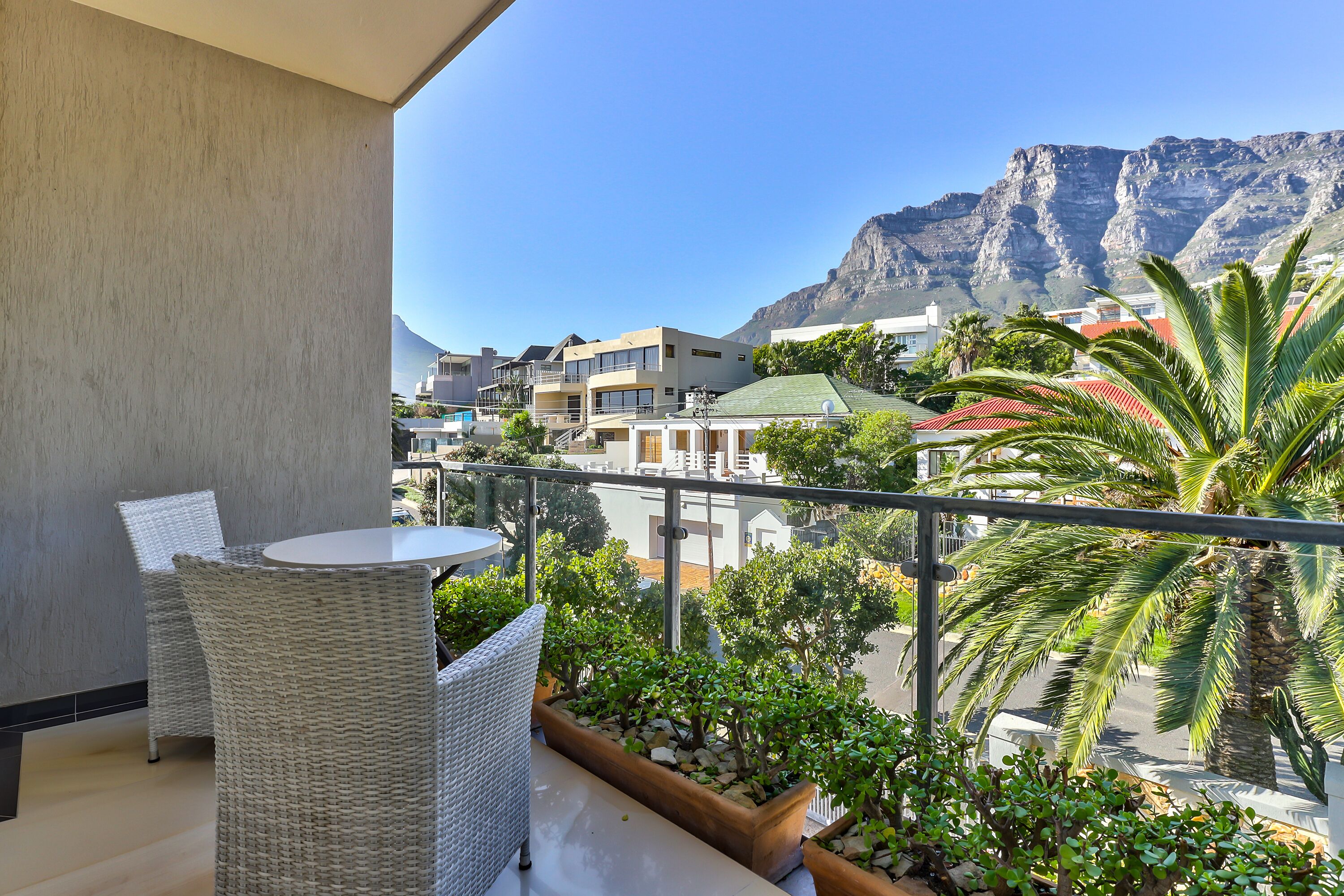 A balcony with wicker furniture, a view of buildings, and a mountain in the background.