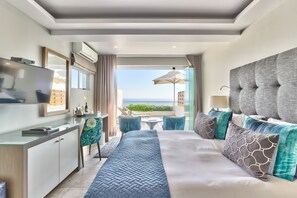 A modern hotel room with a large bed, a desk, and a balcony with a view. - Ocean View House (Cape Town)