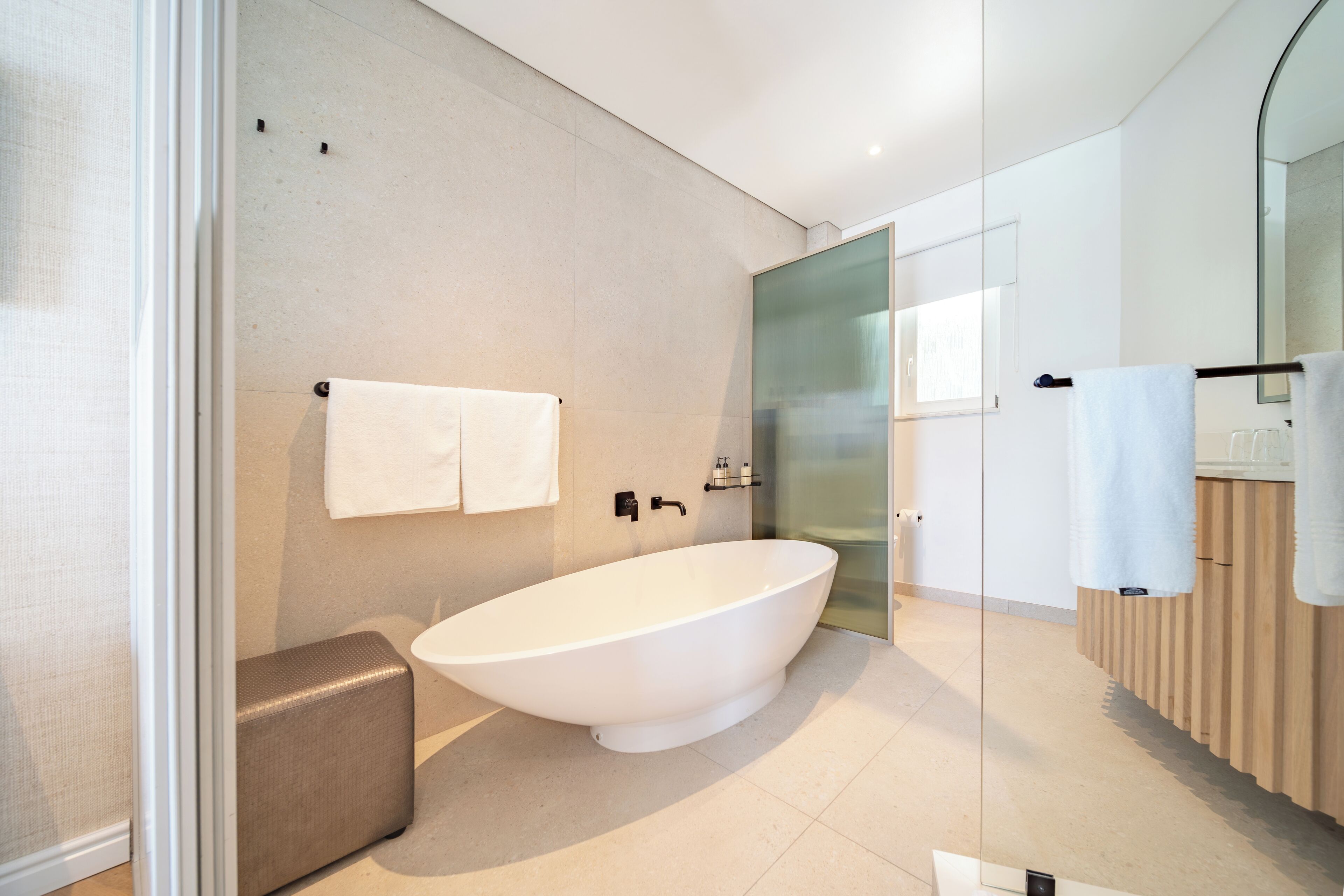 A modern bathroom with a freestanding bathtub, a glass shower enclosure, and a wooden vanity.