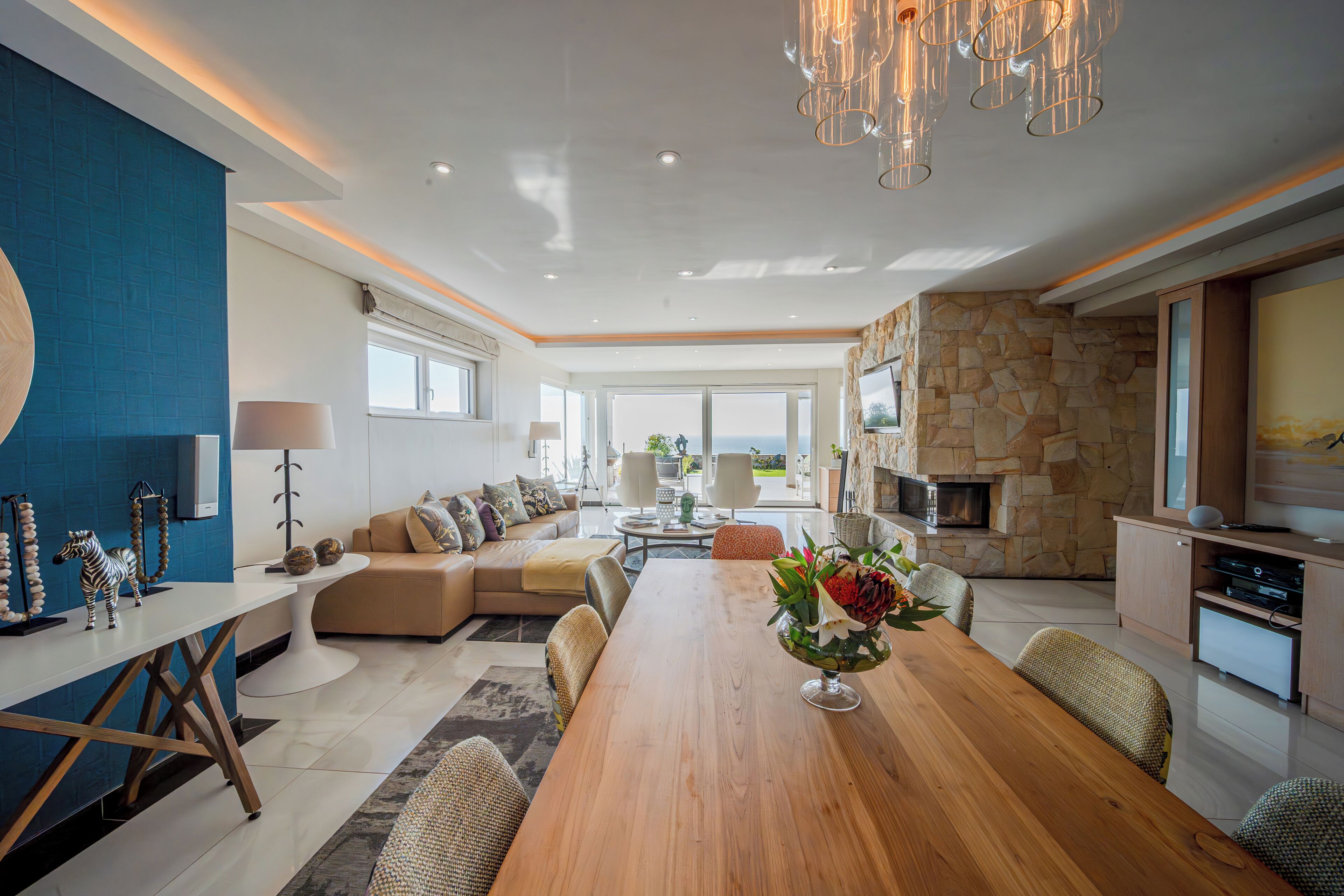 Amplia sala de estar con una mesa de comedor de madera, un conjunto de sofás y una pared de acento de piedra.