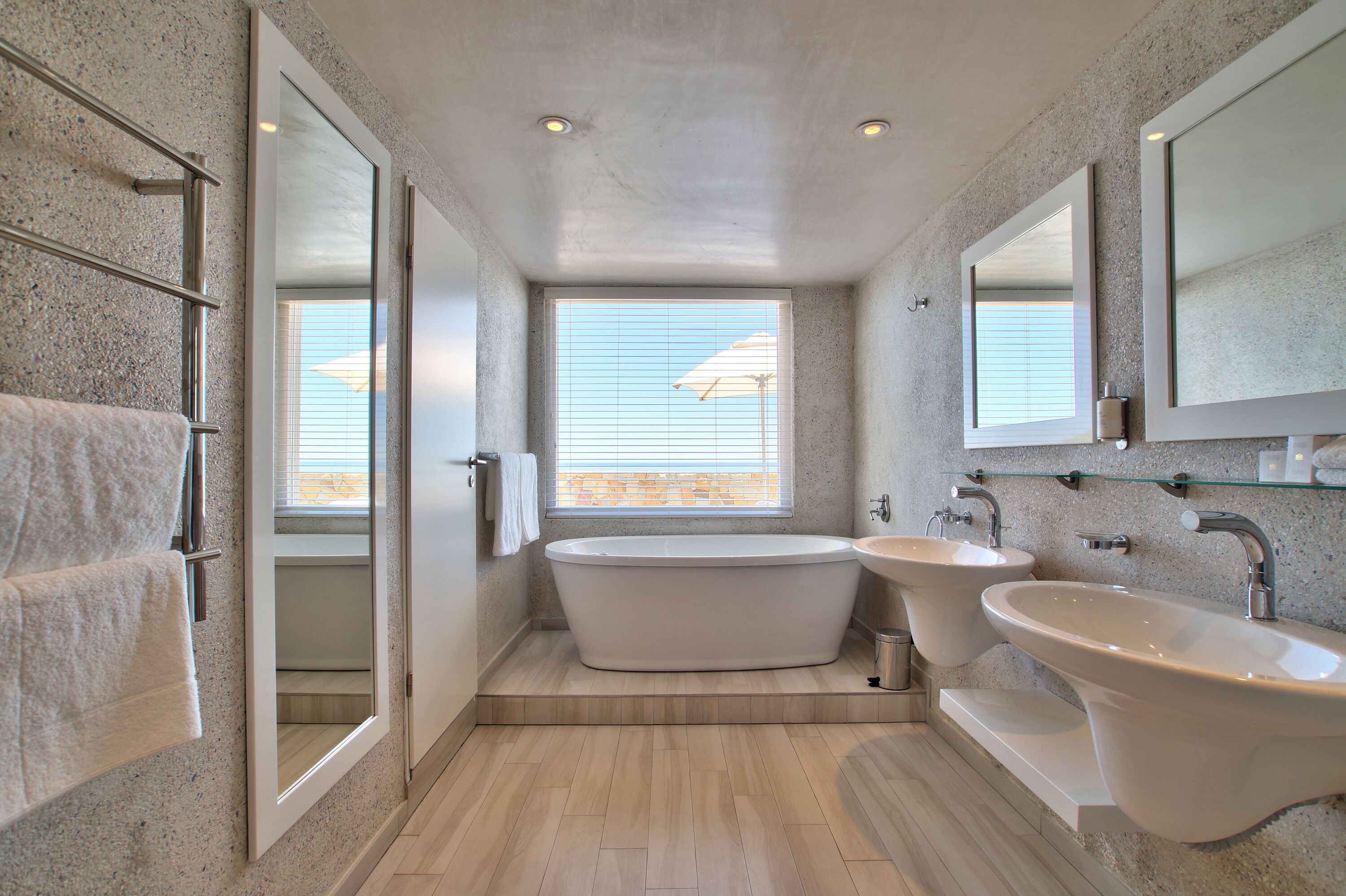 A modern bathroom with a freestanding bathtub, two sinks, and a large mirror.