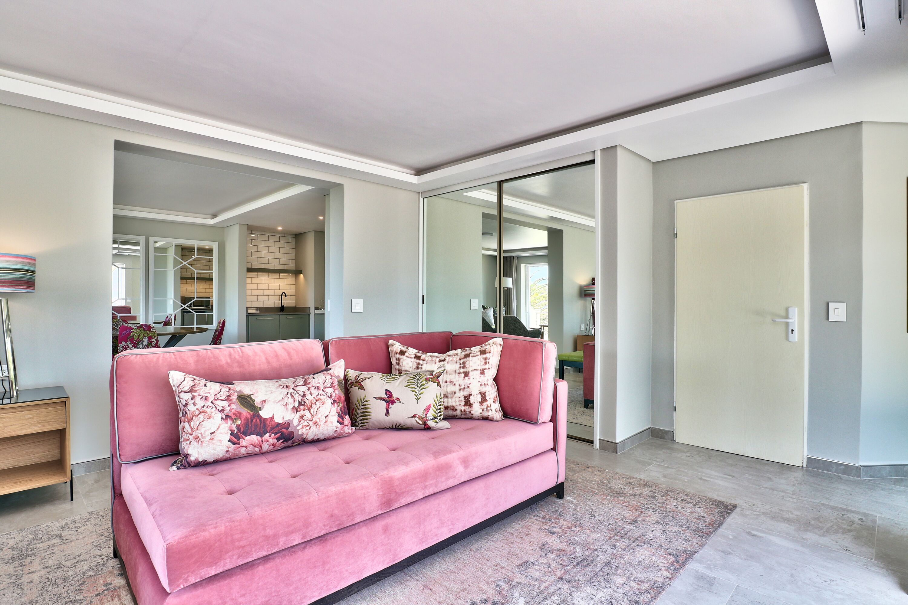A modern living room with a pink sofa, a wooden side table, and a patterned rug.