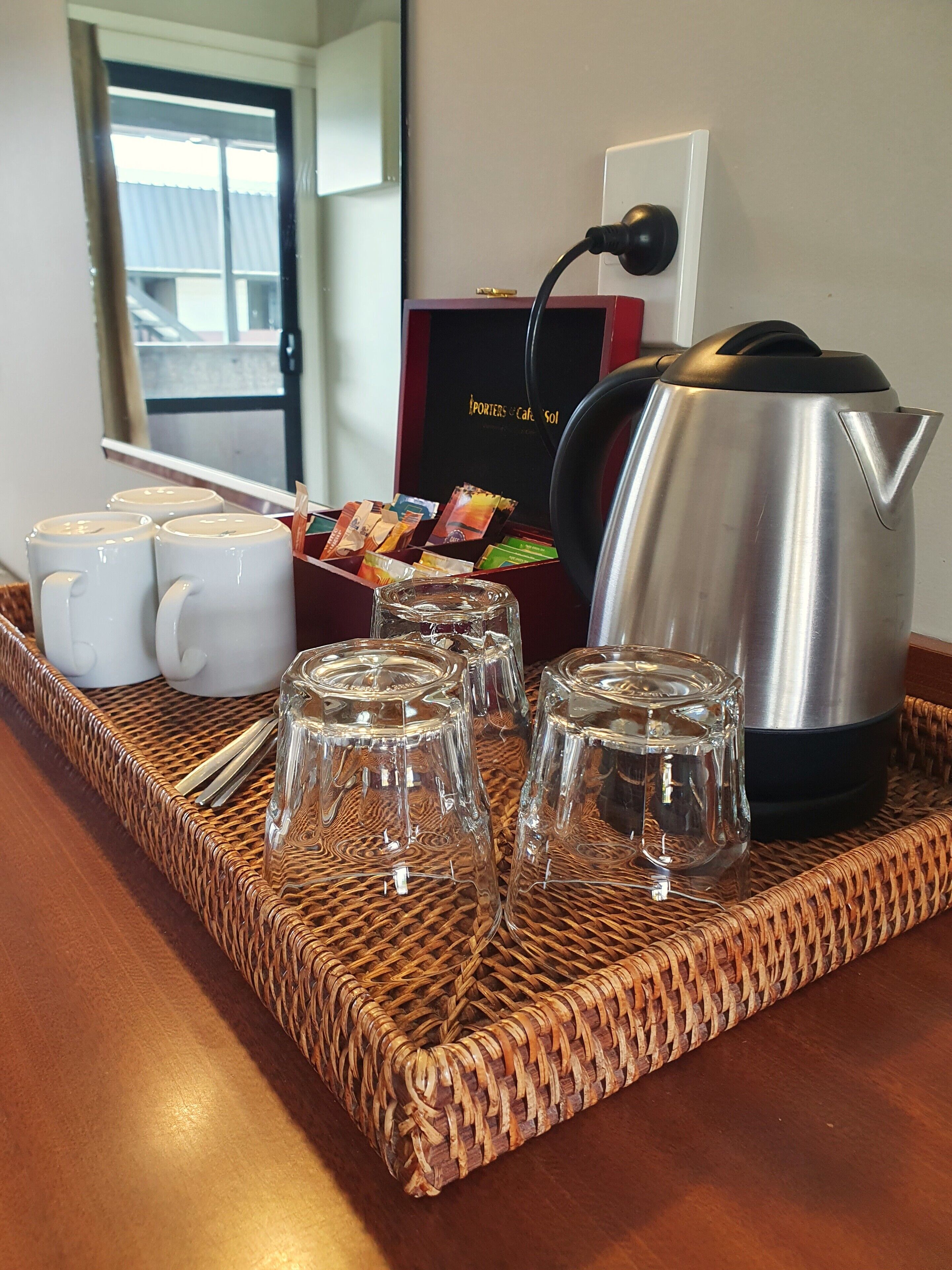 A tray with coffee mugs, a glass carafe, and a coffee pot on a woven mat.