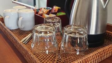 A tray with coffee mugs, a glass carafe, and a coffee pot on a woven mat.