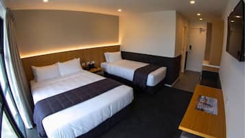 A hotel room with two beds, a desk, and a TV.