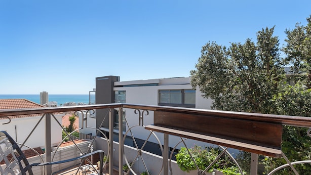 A balcony with a view of the sea, metal railings, and potted plants. - Maartens Guesthouse (Cape Town)