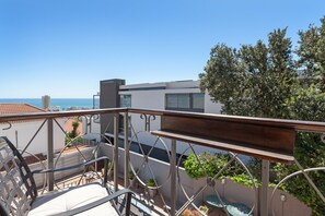 Un balcon avec vue sur la mer, des balustrades en métal et des plantes en pot.