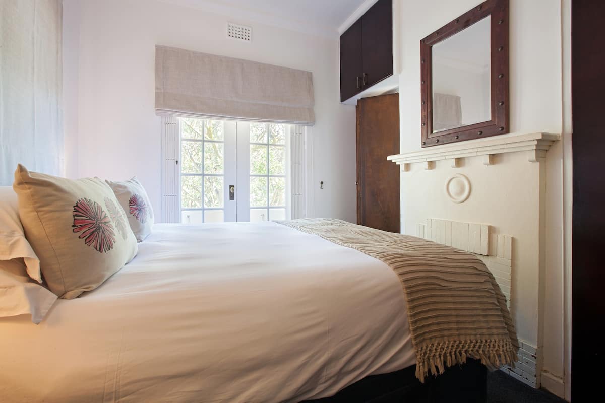 Ein Schlafzimmer mit einem großen Bett, einem Fenster mit Blick, einem Spiegel und einer Tür.