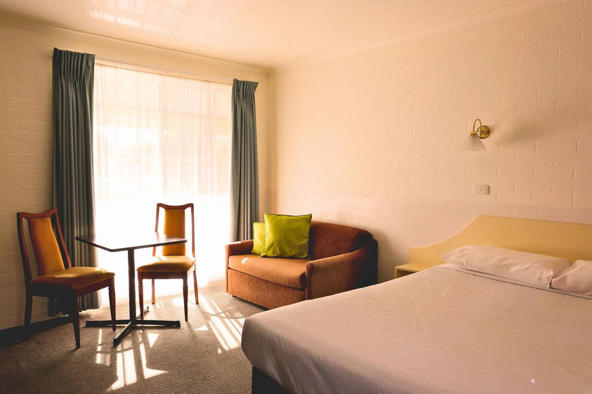 A hotel room with a bed, a sofa, a chair, and a small table.