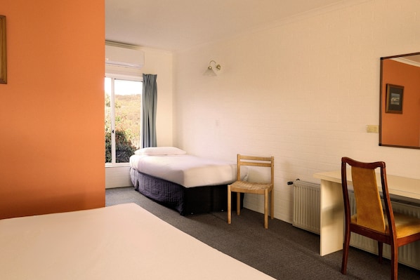 Una habitación de hotel con cama, escritorio, silla y radiador.
