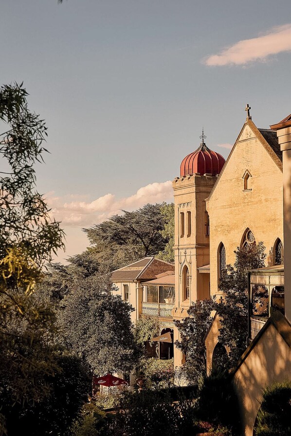A church with a prominent red dome and a bell tower, surrounded by lush greenery and other buildings.