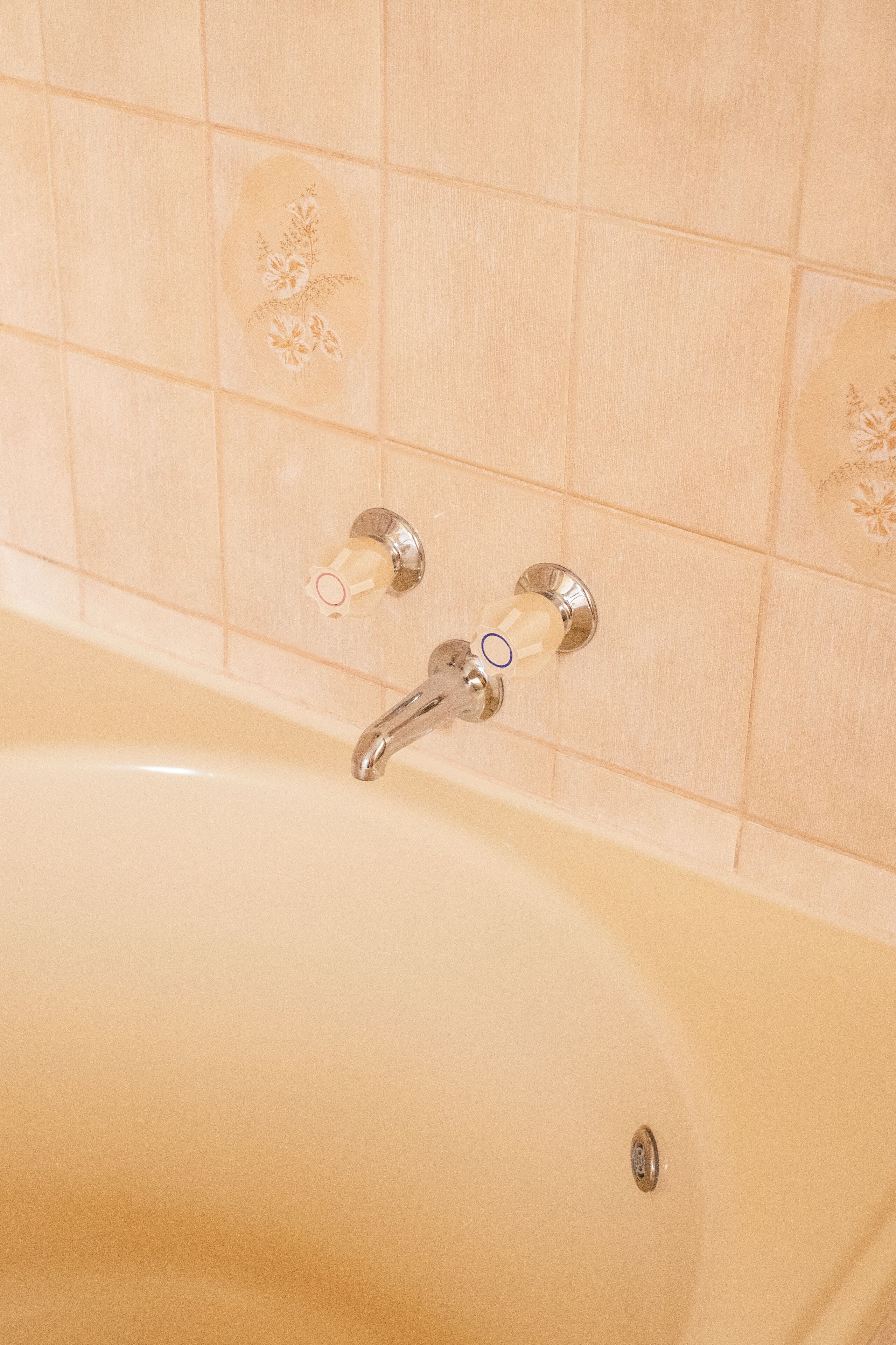 Une baignoire dotée d’un robinet chromé et de deux distributeurs de savon fixés au mur.