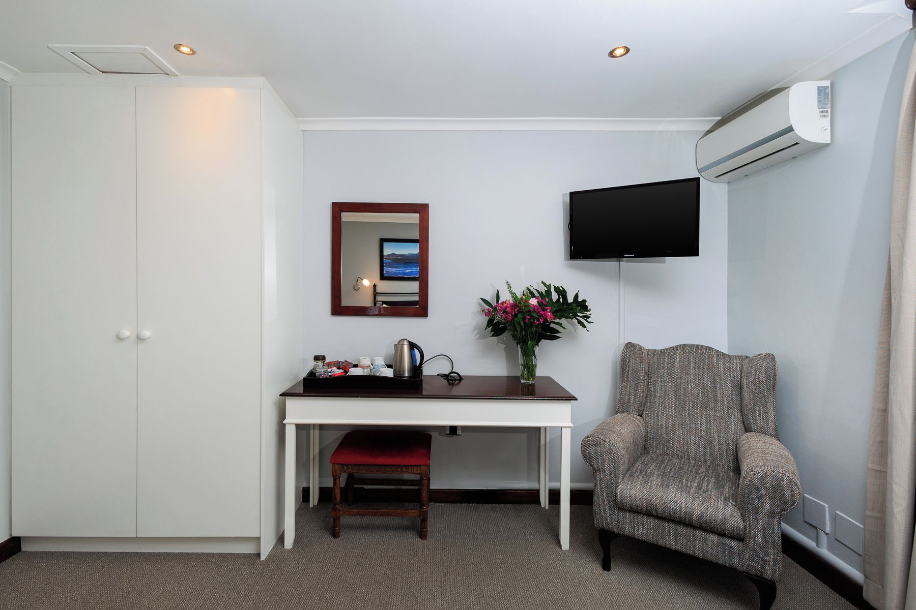 Une chambre d’hôtel équipée d’un bureau, d’une chaise, d’une télévision et d’un appareil de climatisation.
