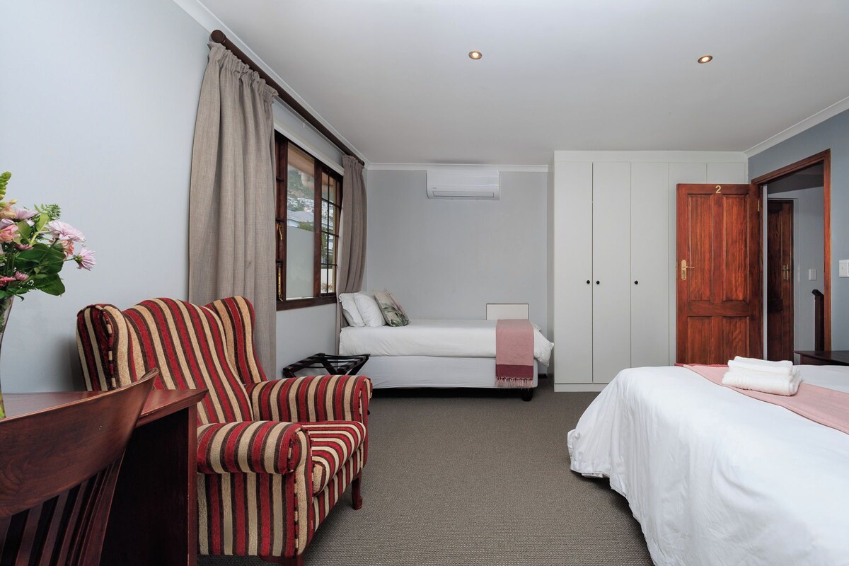 Una habitación de hotel con una cama, una silla, un escritorio y un armario.