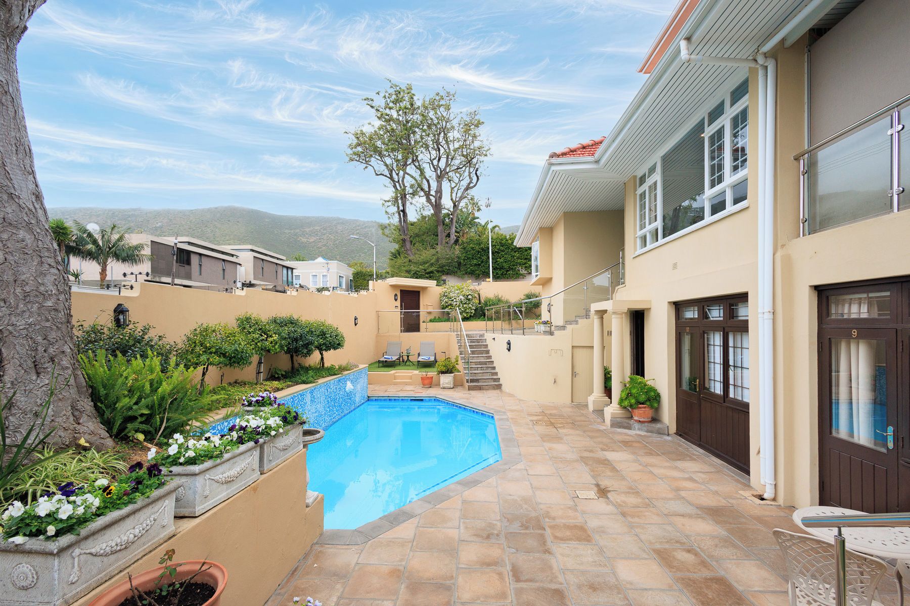 Propiedad residencial con piscina, una escalera que conduce a un segundo piso y vistas del paisaje circundante.