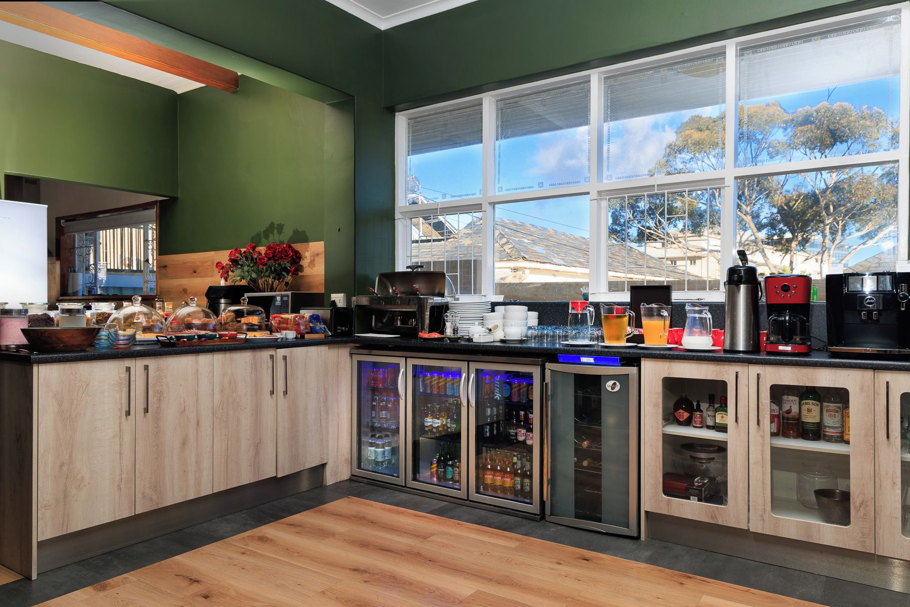 A modern kitchen with a large window, wooden cabinets, and various appliances.