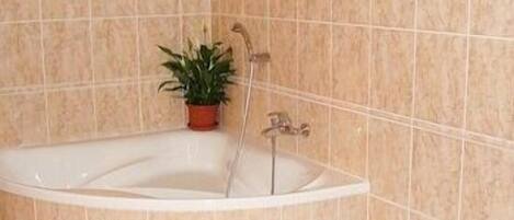Un baño con una bañera independiente, un lavamanos y una planta en maceta.