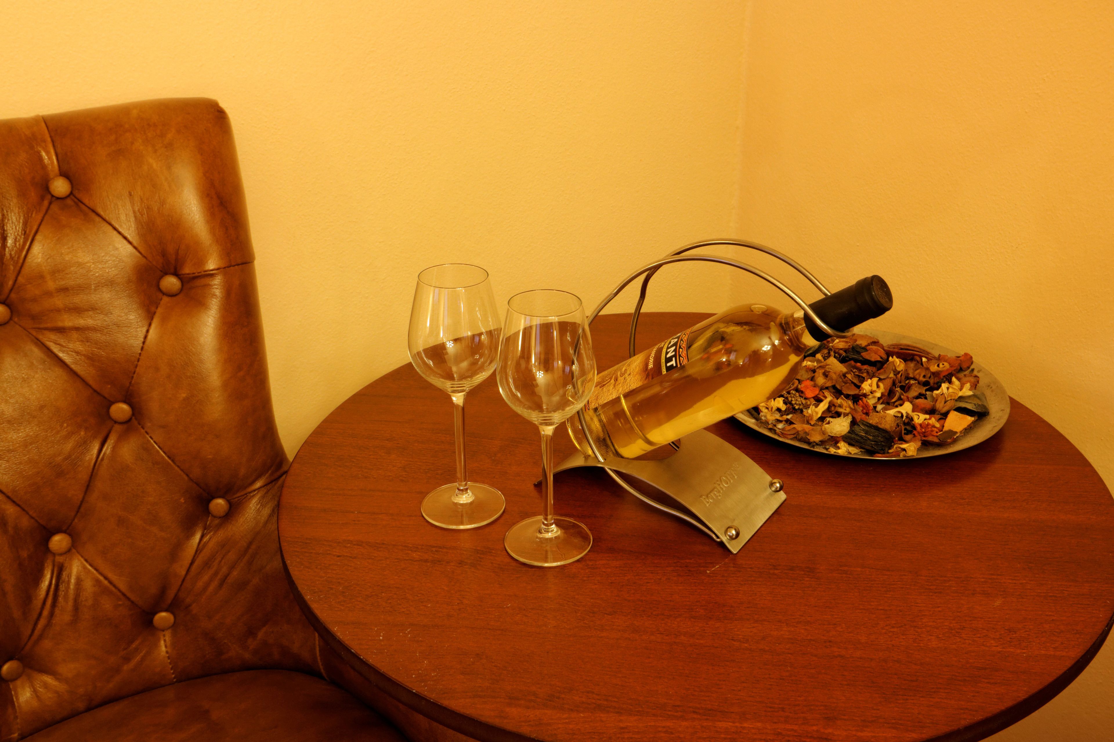 A round wooden table with two wine glasses, a bottle of wine, and a plate of food.