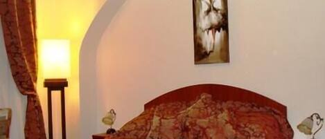 A hotel room with a bed, a nightstand, a lamp, and a painting on the wall.