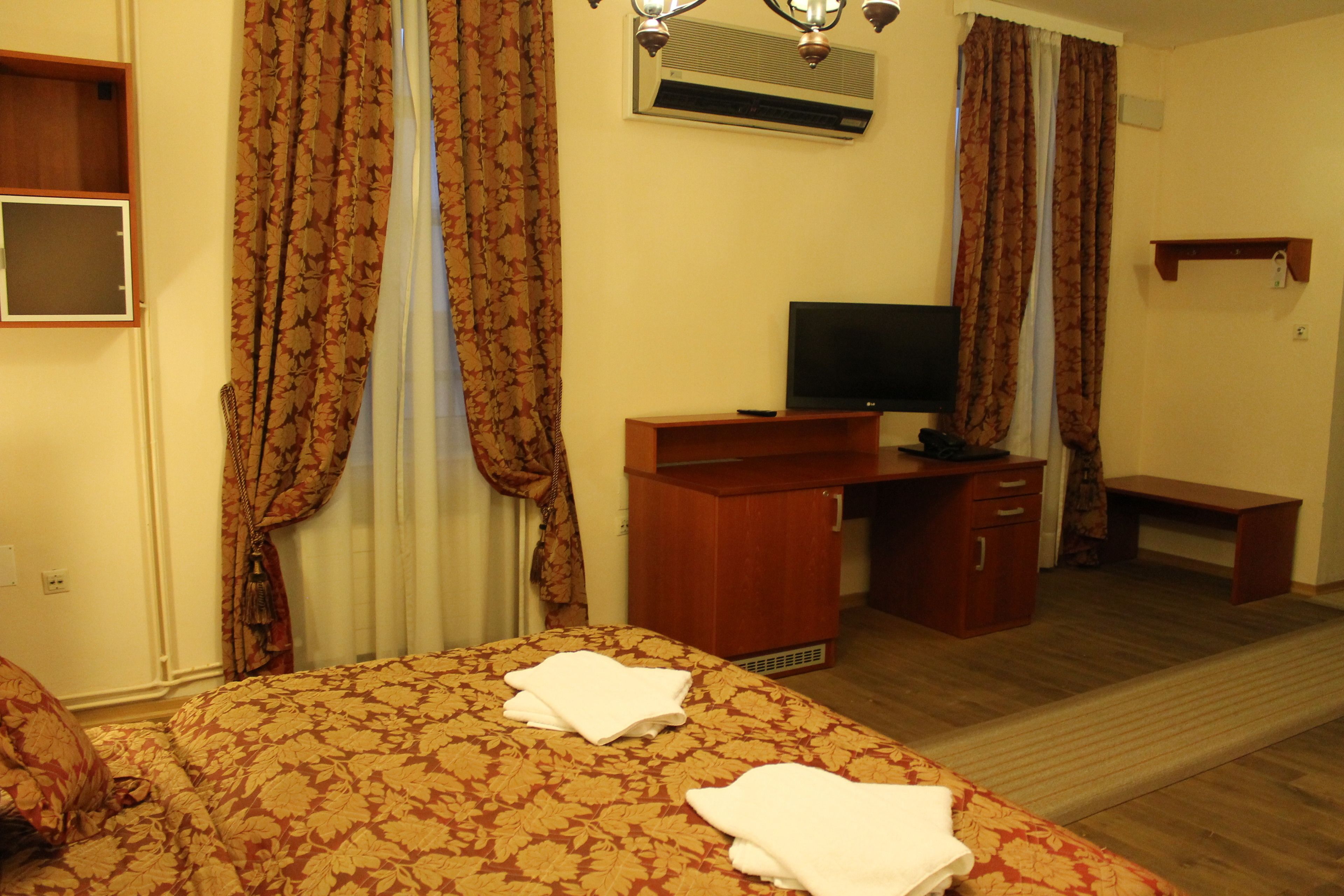 Una habitación de hotel con cama, escritorio, televisor y aire acondicionado.