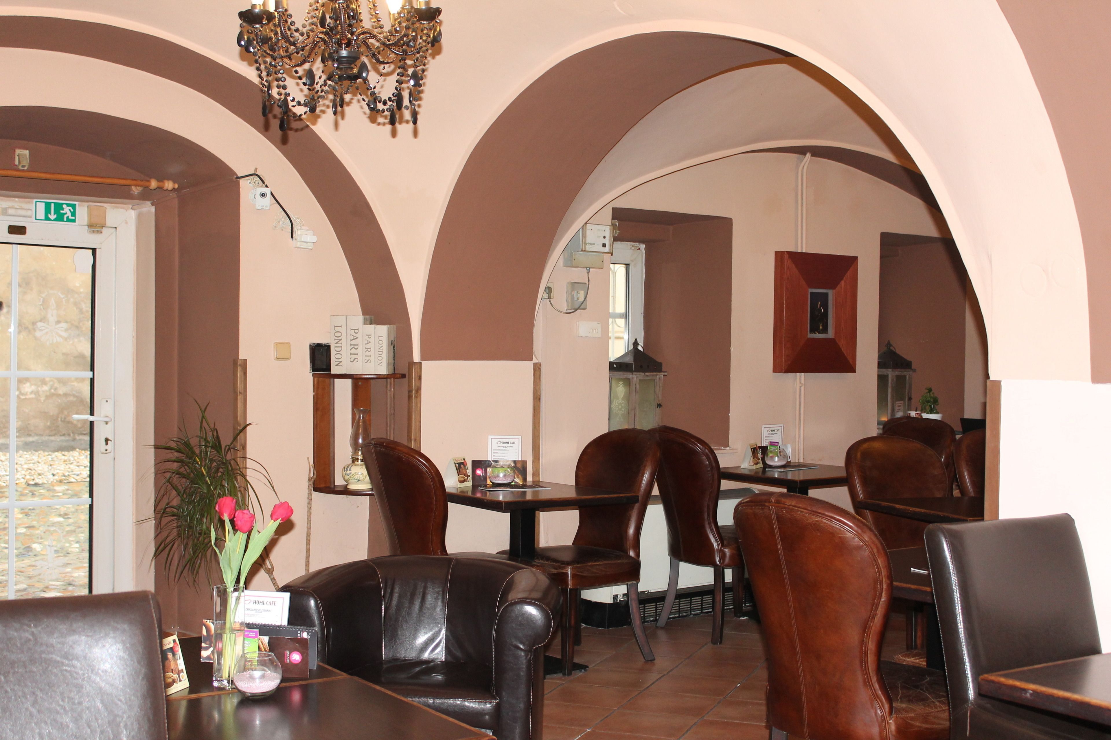 A restaurant with brown leather chairs, a chandelier, and a vase with flowers on the table.