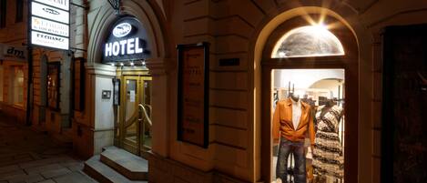 A hotel entrance with an arched doorway, a sign for the Ocean Star Hotel, and a display window with mannequins and shoes.