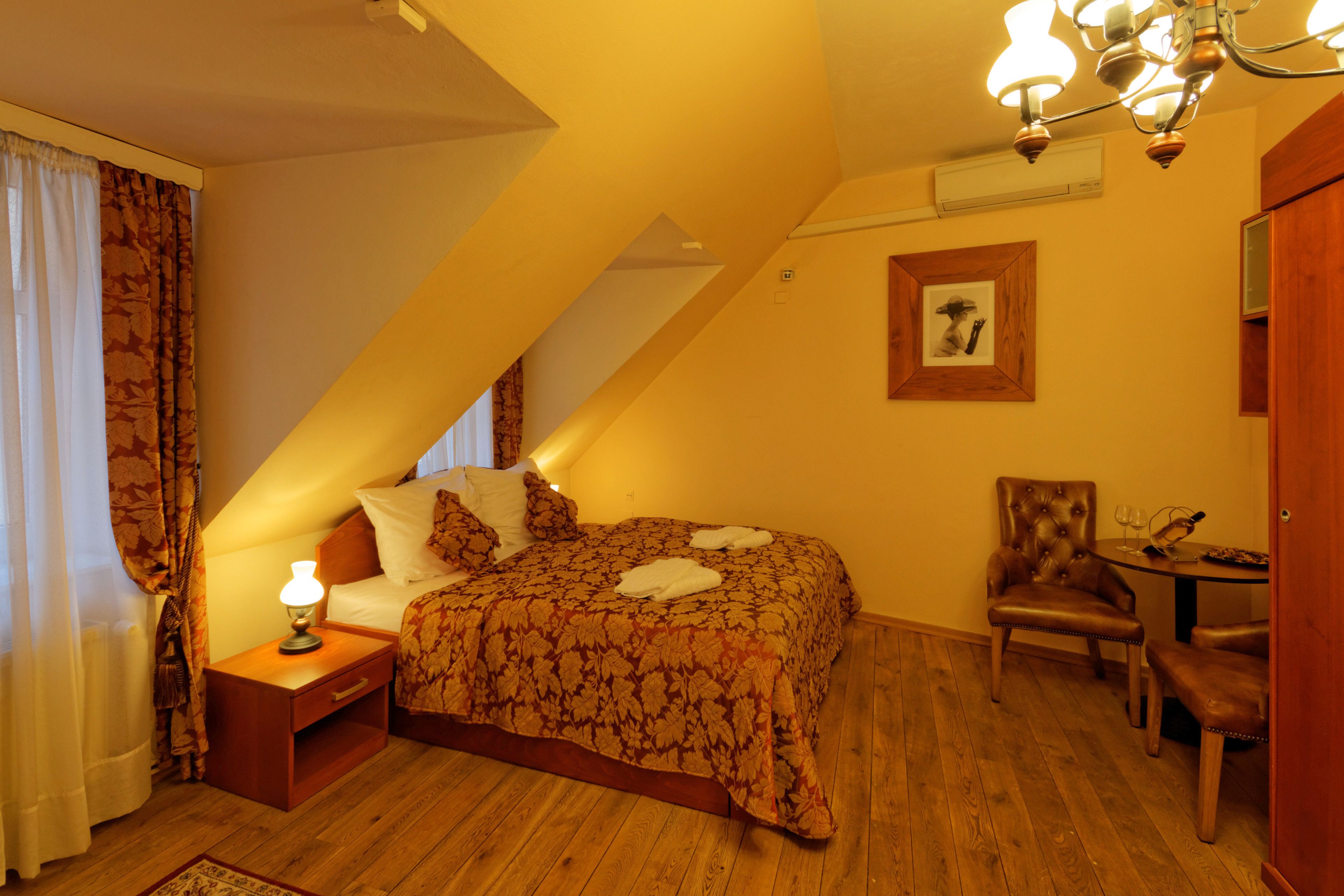 A bedroom with a bed, nightstand, chair, and table.