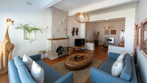 Een moderne woonkamer met een open haard, blauwe banken, een televisie en decoratieve objecten.
