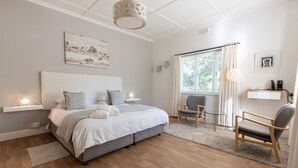 Een moderne slaapkamer met een groot bed, nachtkastjes, een stoel en een raam met gordijnen.