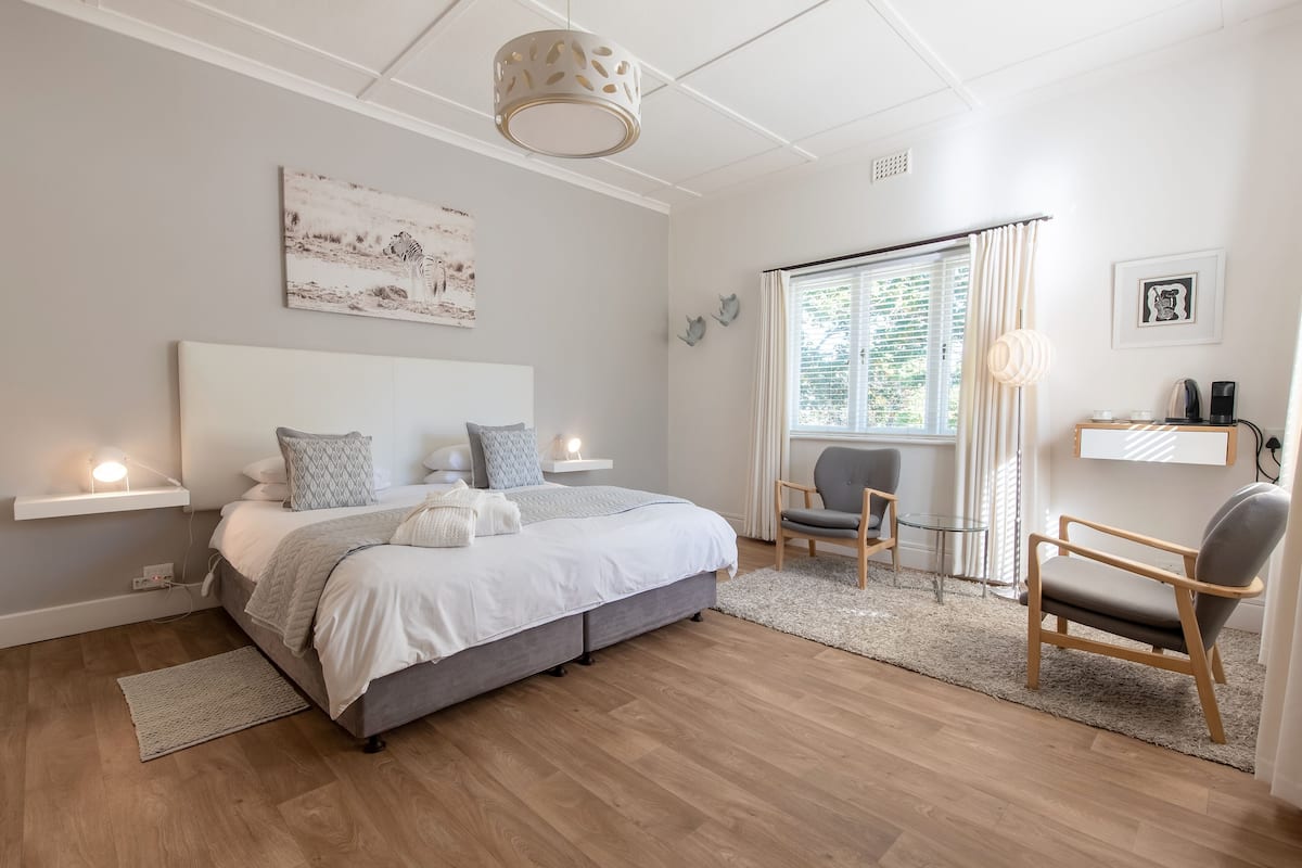 Een moderne slaapkamer met een groot bed, nachtkastjes, een stoel en een raam met gordijnen.