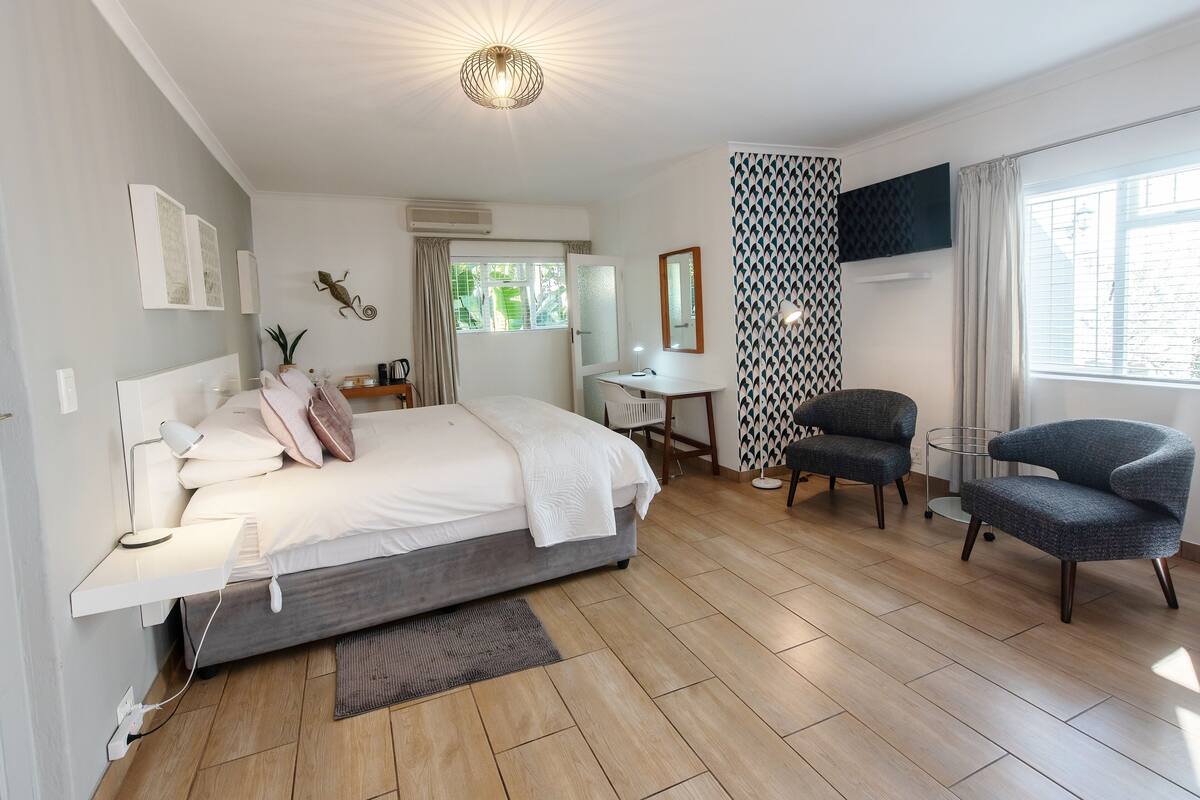 Een moderne hotelkamer met een bed, bureau en twee stoelen.