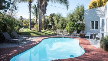Una piscina al aire libre, sillones reclinables de piscina