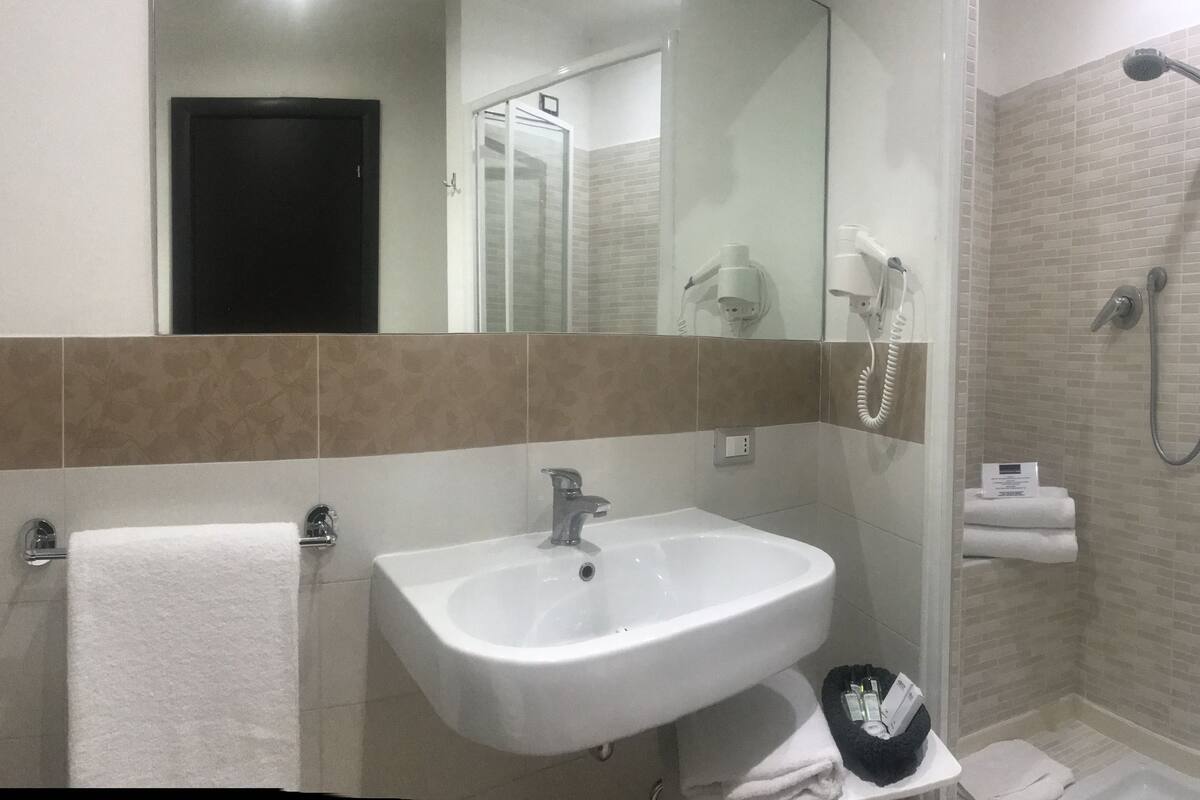 Un baño moderno con lavabo, espejo y ducha.