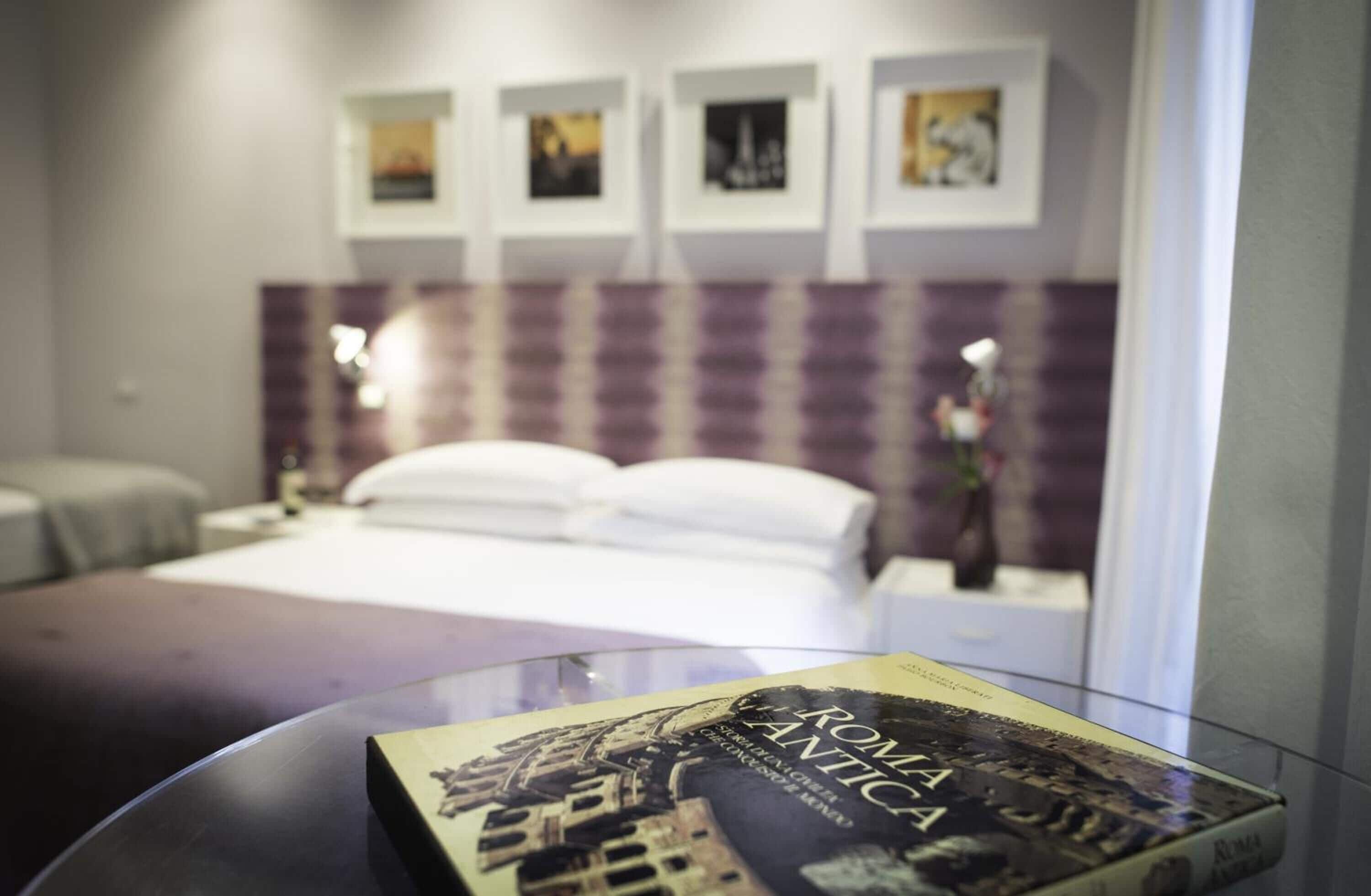Quarto de hotel com cama, mesas de cabeceira e quadros na parede.