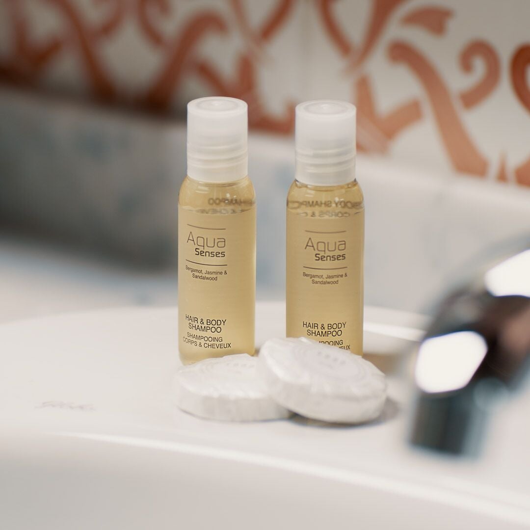 Deux bouteilles de shampoing Aqua Senses sur une surface blanche, avec un arrière-plan flou.