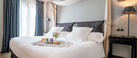 A neatly made bed with a tray of breakfast items, a bedside lamp, and a nightstand.