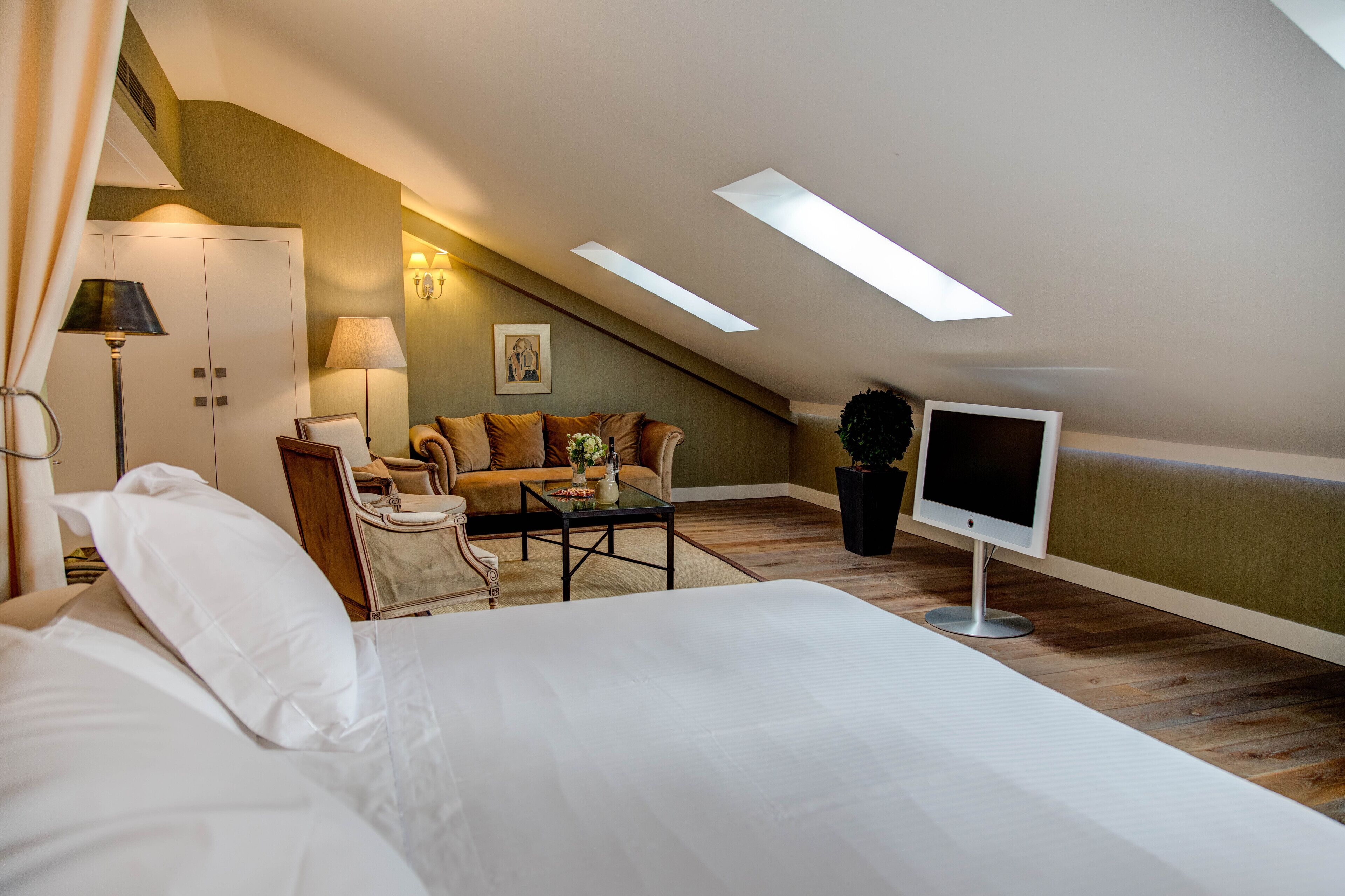 Una habitación de hotel moderna con una cama grande, un sofá, una mesa de centro y un televisor.