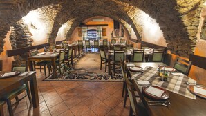 A restaurant with stone arches, wooden tables, and chairs arranged for dining.