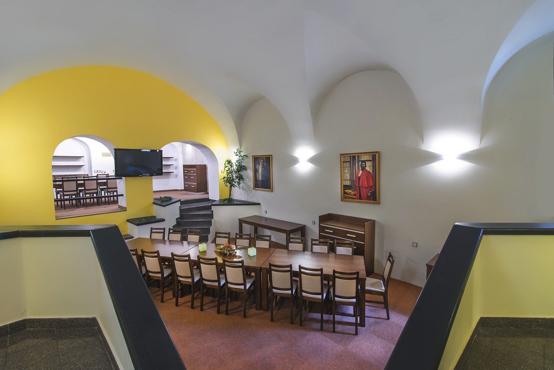 Un comedor con una mesa alta y sillas, una escalera y un televisor montado en la pared.
