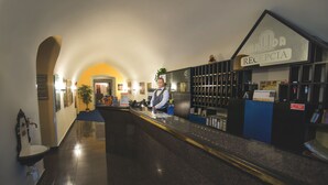A hotel reception area with a receptionist, a reception desk, and a sign indicating the reception.