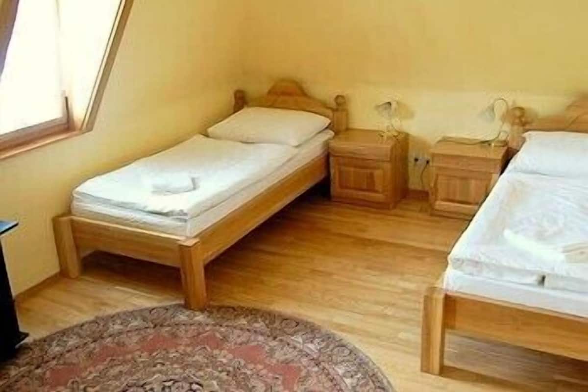 Una habitación pequeña y acogedora con dos camas de madera, una mesita de noche y una ventana.