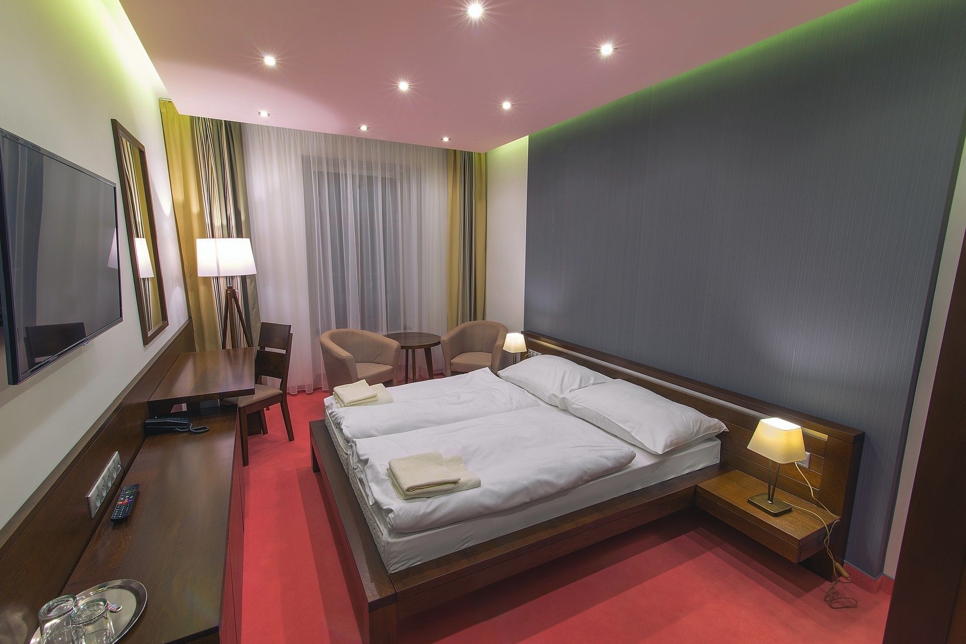 Une chambre d’hôtel avec un grand lit, des tables de chevet, un bureau, une chaise et un téléviseur.