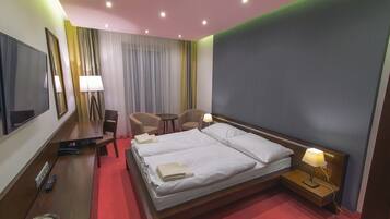 Une chambre d’hôtel avec un grand lit, des tables de chevet, un bureau, une chaise et un téléviseur.