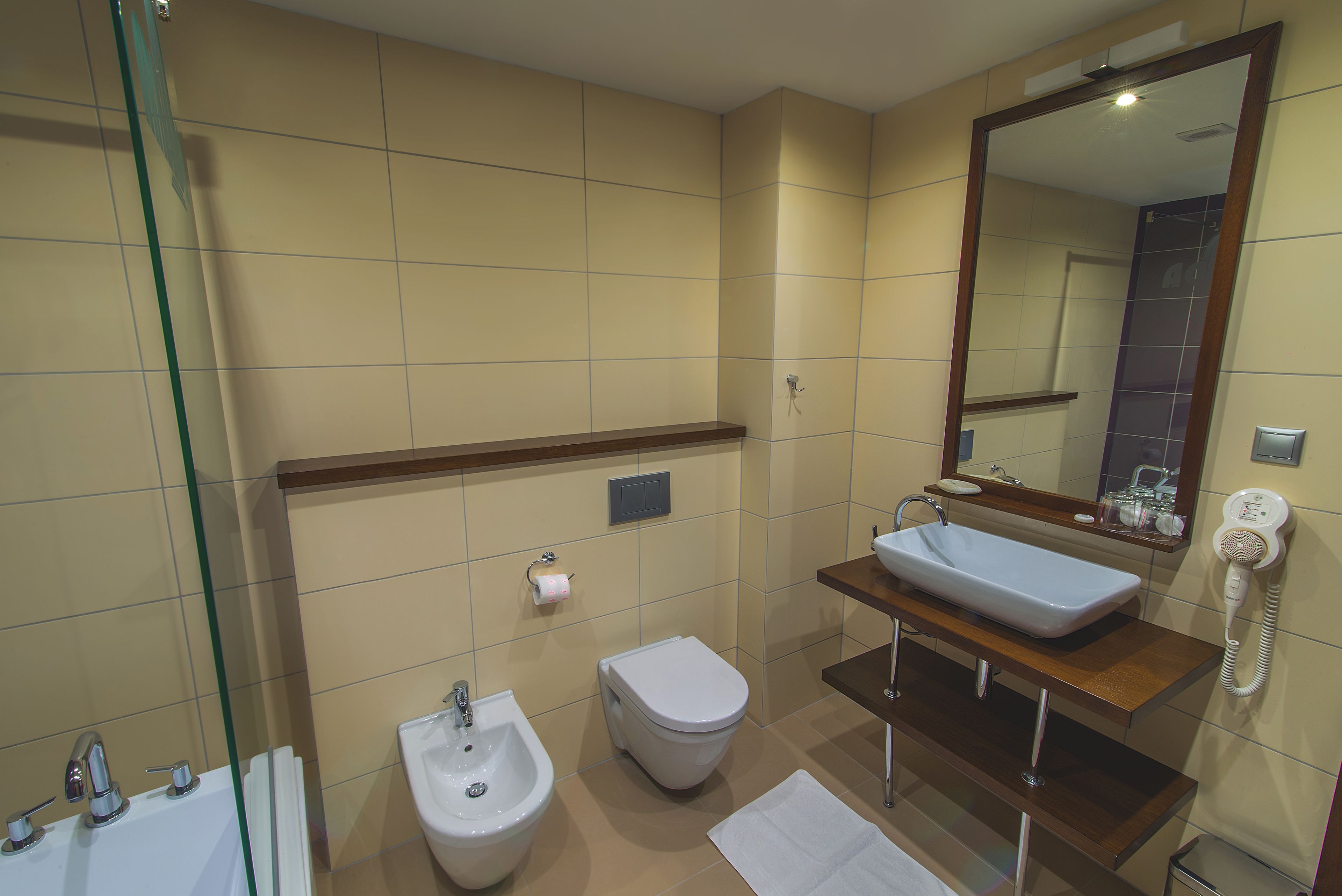 A modern bathroom with a bidet, a sink, and a mirror.