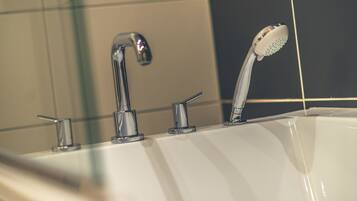 Ein Badezimmer mit einer weißen Badewanne, einer Chrom-Dusche und einem Chrom-Wasserhahn.