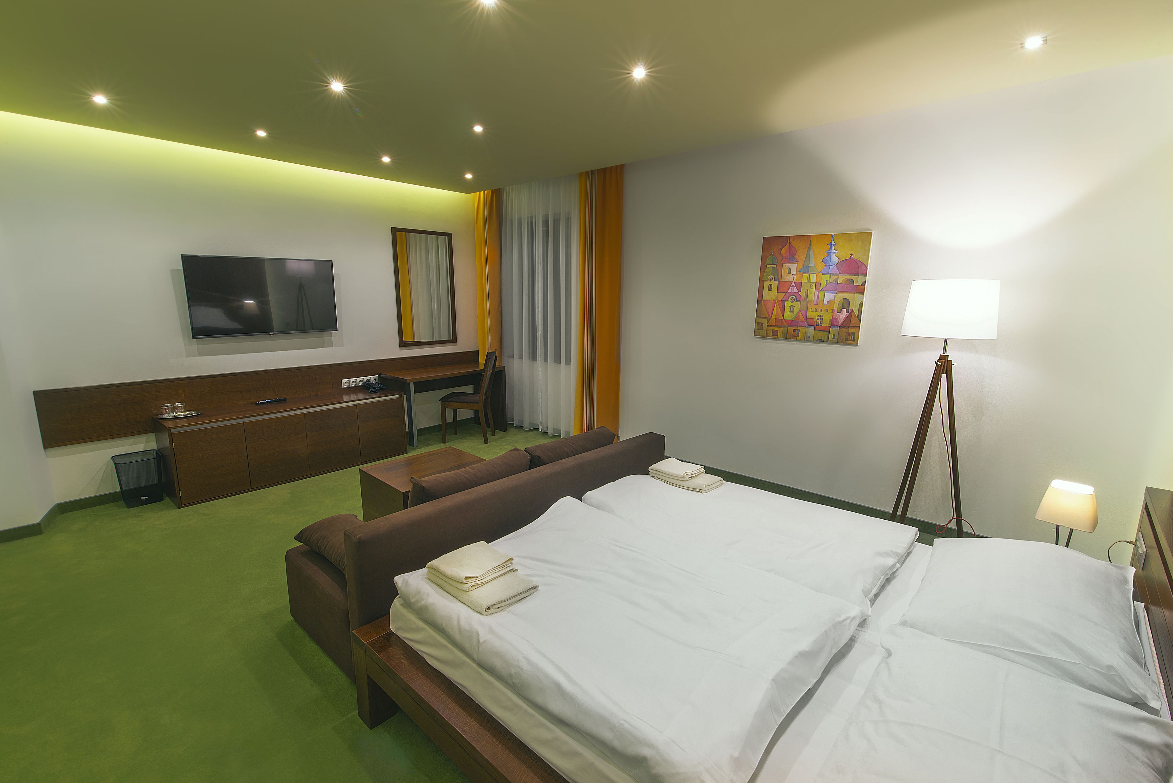 A hotel room with a bed, a sofa, a desk, and a TV.