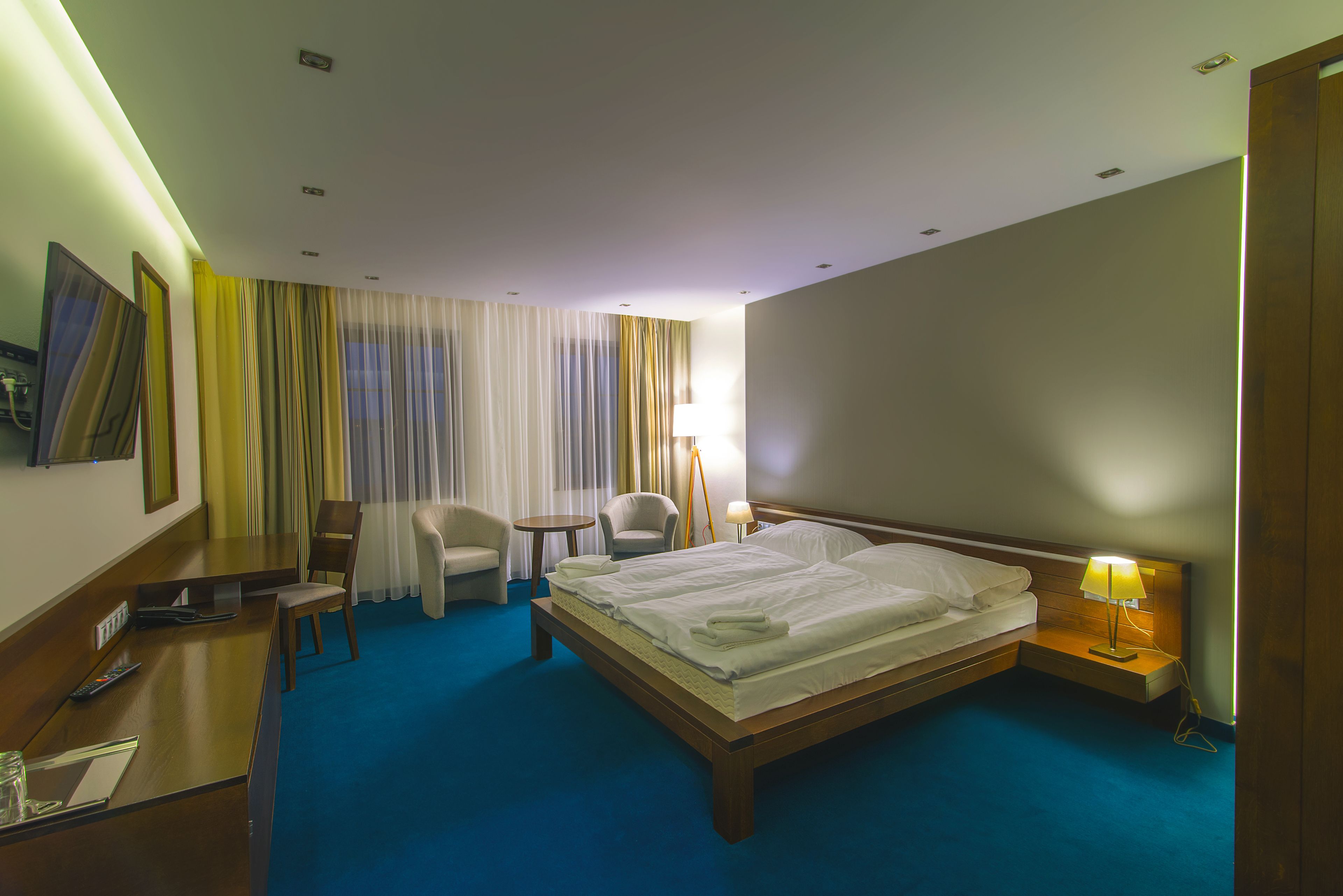 Una habitación de hotel con una cama grande, dos sillones, un escritorio y una lámpara.