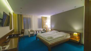 Una habitación de hotel con una cama grande, dos sillones, un escritorio y una lámpara.